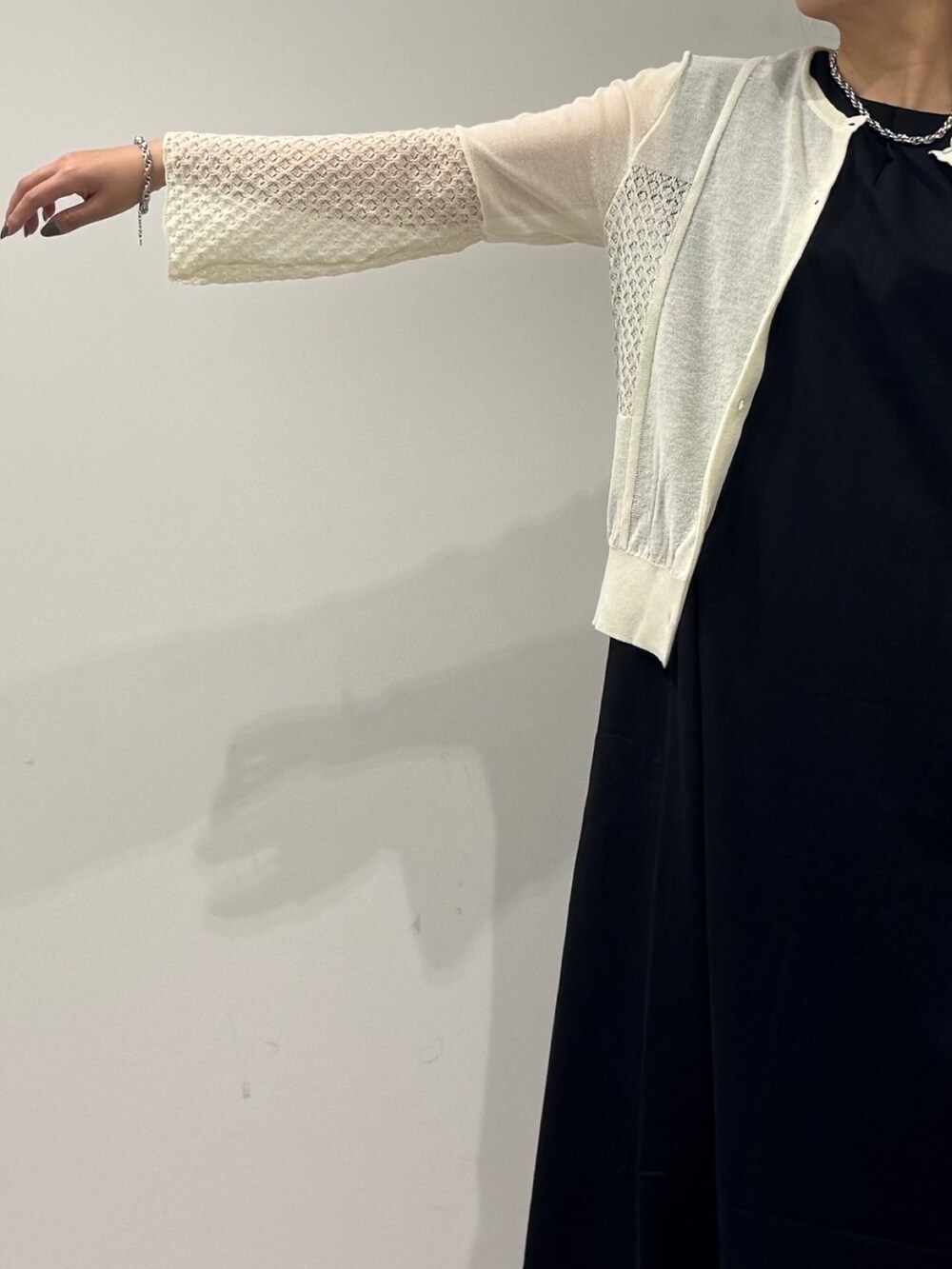 シルバー系のかごバッグ、ブラック系のワンピース、ホワイト系のカーディガン/ボレロを着用したレディースの秋コーディネートの7枚目の写真