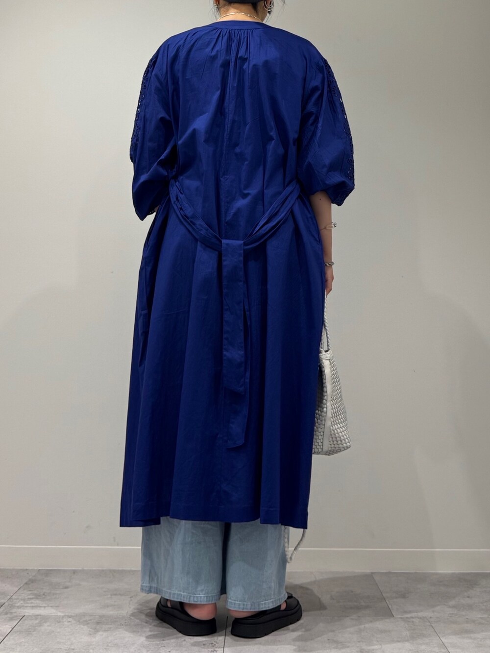 ホワイト系のトートバッグ、ブルー系のデニムパンツ、ブラック系のサンダルを着用したレディースの秋コーディネートの4枚目の写真