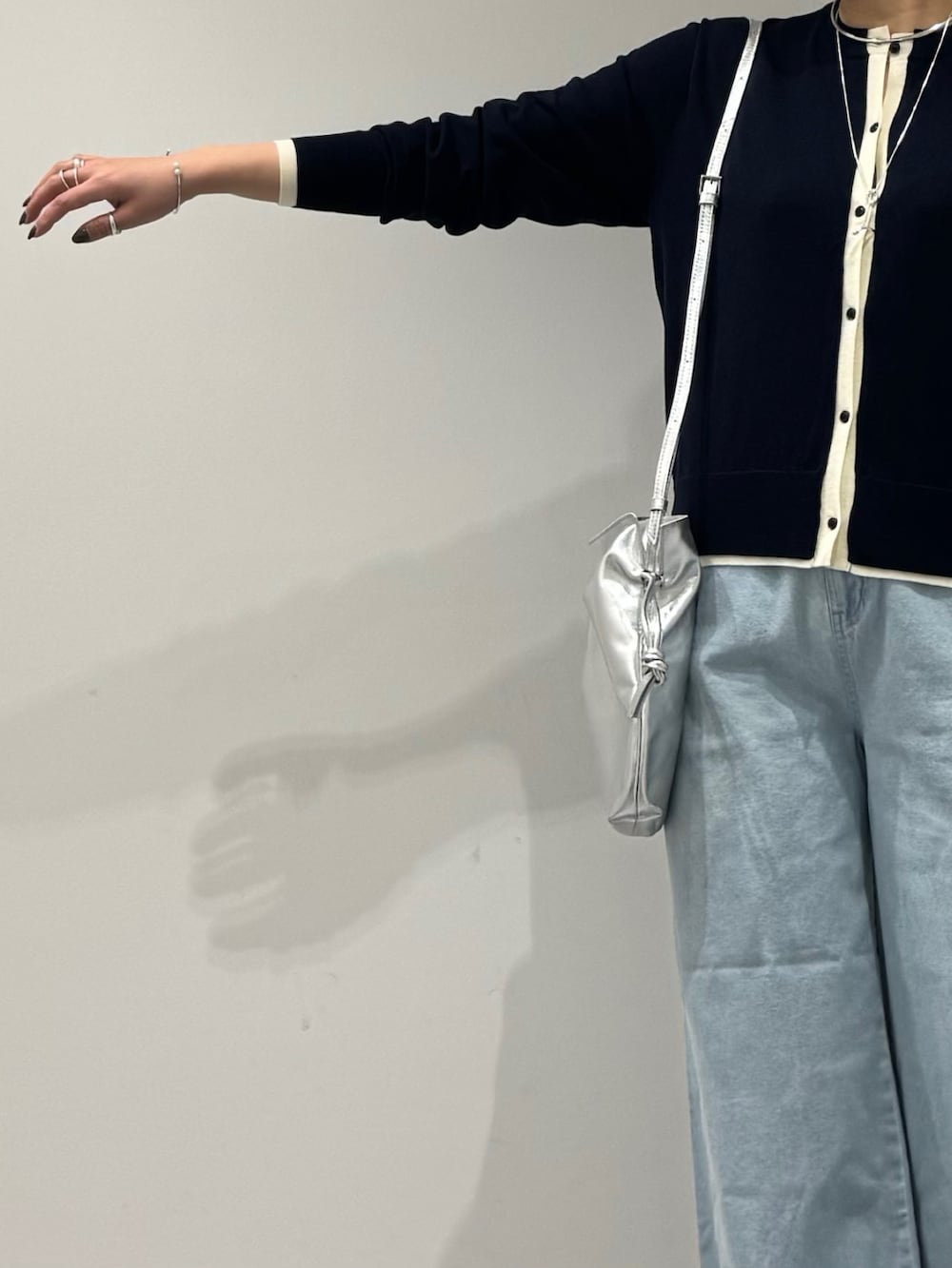 シルバー系のショルダーバッグ、ブルー系のデニムパンツ、ブルー系のカーディガン/ボレロを着用したレディースの春コーディネートの6枚目の写真