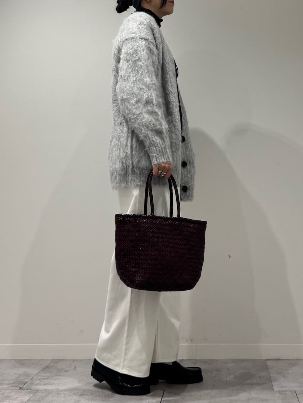 パープル系のトートバッグ、ホワイト系のデニムパンツ、ブラック系のローファーを着用したレディースの冬コーディネートの3枚目の写真