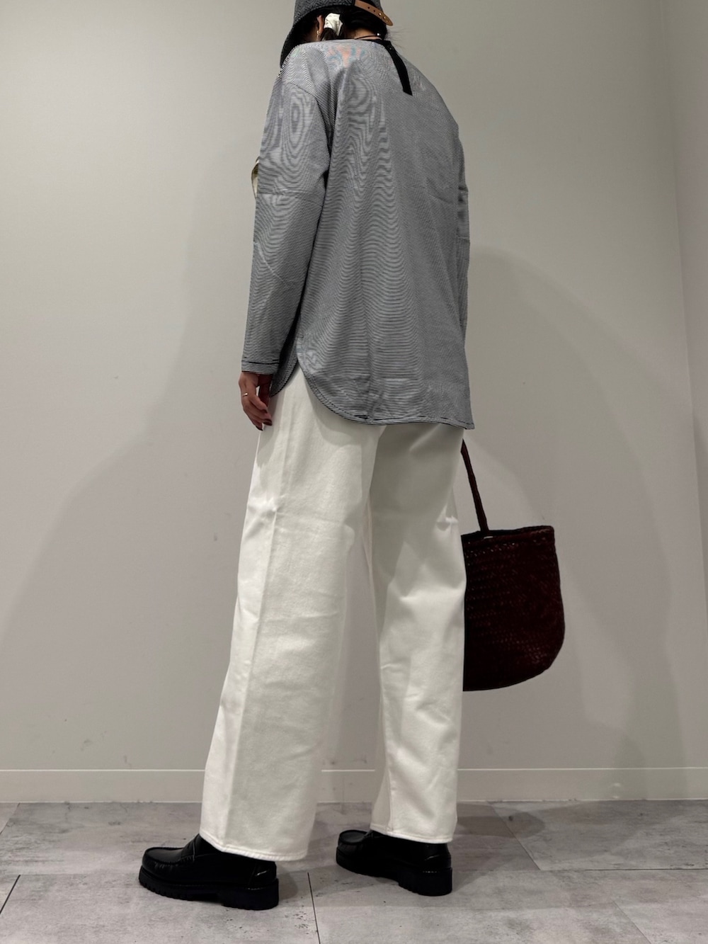 ブラウン系のトートバッグ、ホワイト系のデニムパンツ、ブラック系のローファーを着用したレディースの秋コーディネートの4枚目の写真