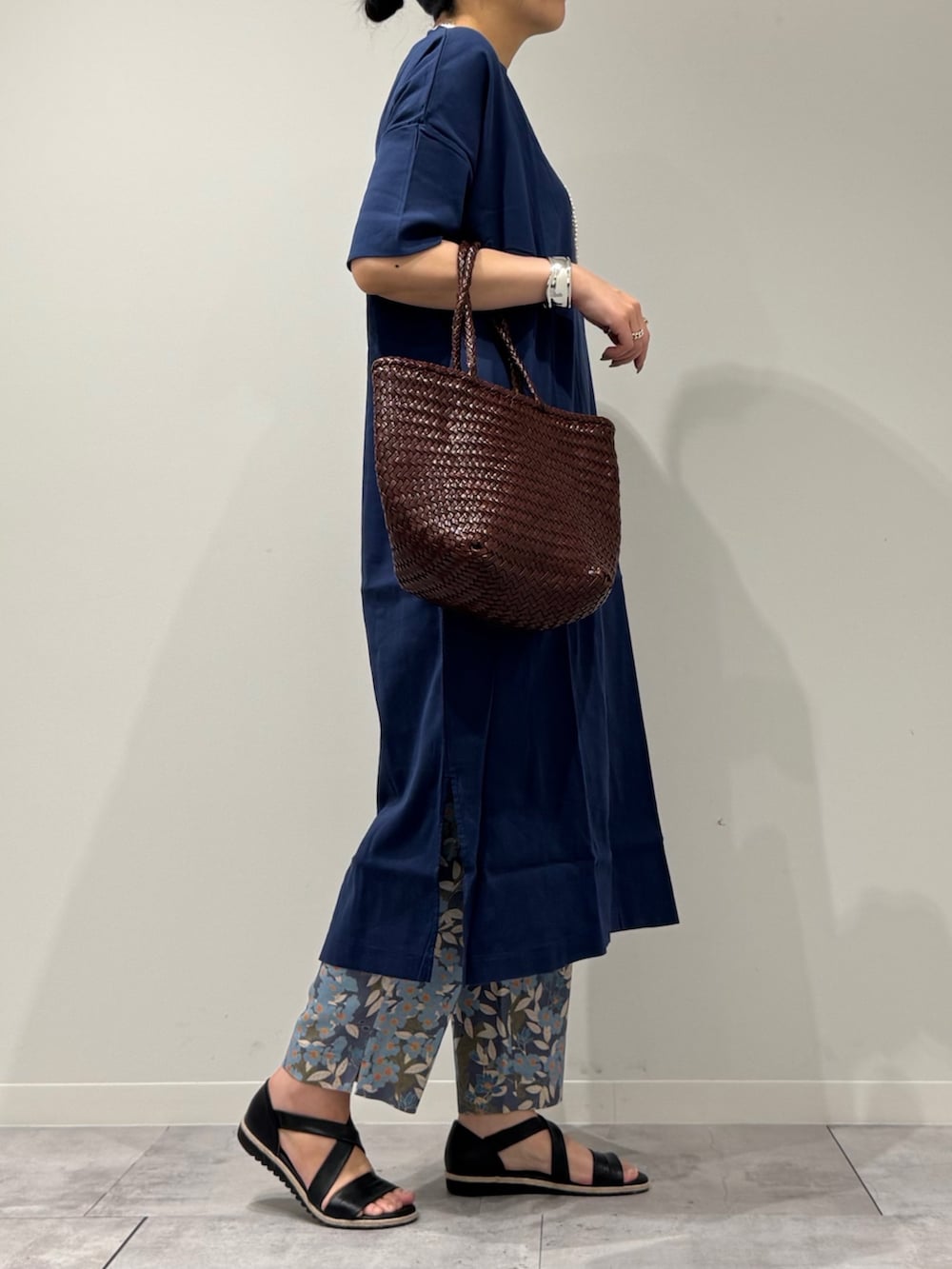 ブラウン系のトートバッグ、ブルー系のその他パンツ、ブラック系のサンダルを着用したレディースの春コーディネートの2枚目の写真