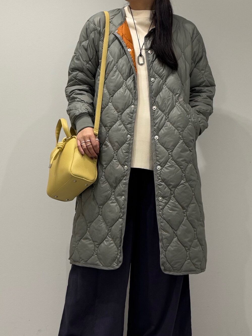 イエロー系のボストンバッグ、ブラック系のローファー、ホワイト系のベストを着用したレディースの秋コーディネートの2枚目の写真