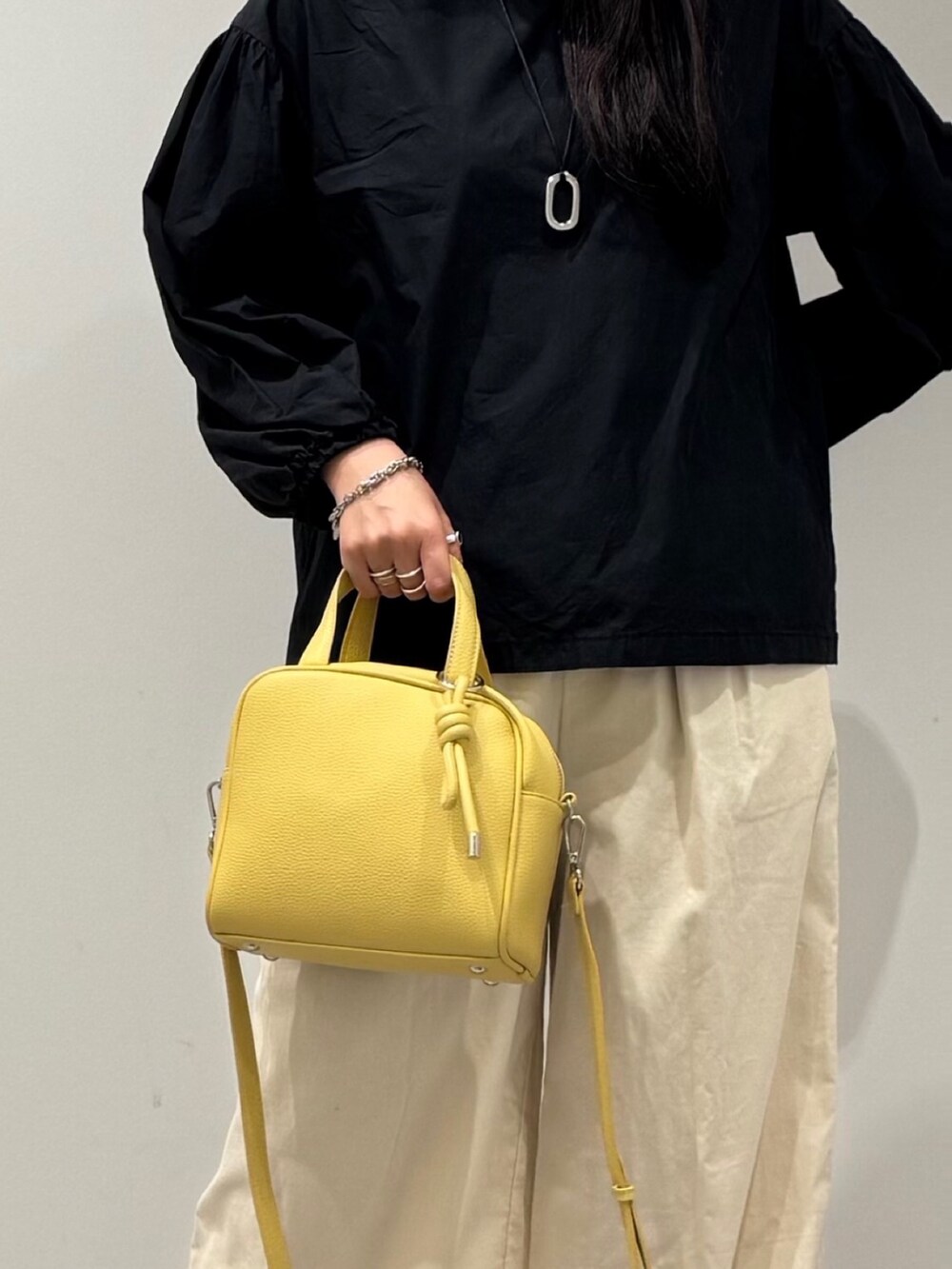 イエロー系のボストンバッグ、ブラック系のローファー、ブラック系のシャツ/ブラウスを着用したレディースの秋コーディネートの8枚目の写真
