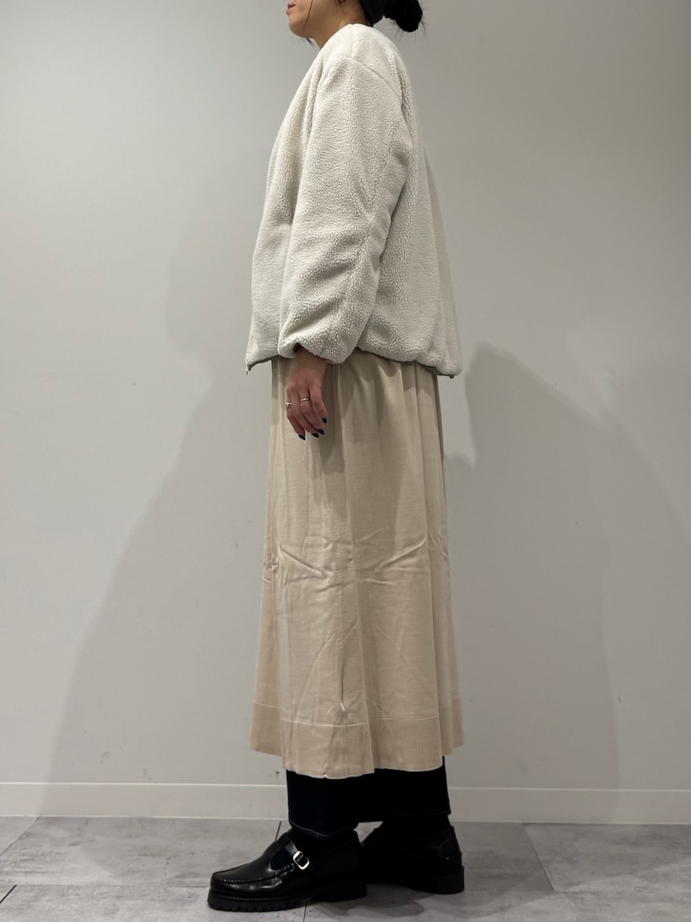 ベージュ系のボストンバッグ、ベージュ系のワンピース、ブルー系のデニムパンツを着用したレディースの春コーディネートの6枚目の写真