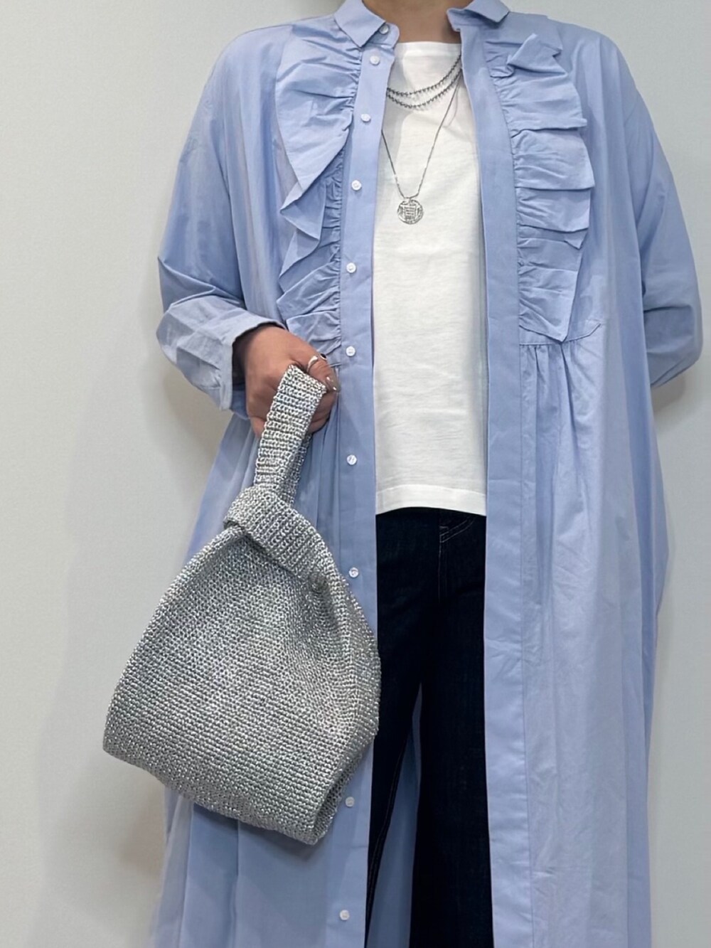ブルー系のシャツワンピース、シルバー系のかごバッグ、ブルー系のデニムパンツを着用したレディースの春コーディネートの9枚目の写真