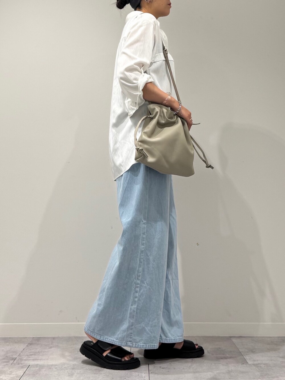 ベージュ系のショルダーバッグ、ブルー系のデニムパンツ、ブラック系のサンダルを着用したレディースの秋コーディネートの2枚目の写真