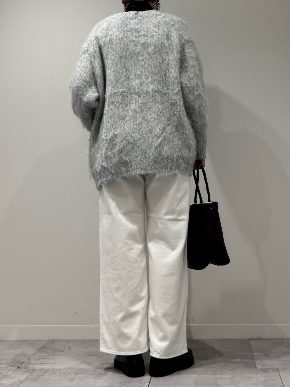 パープル系のトートバッグ、ホワイト系のデニムパンツ、ブラック系のローファーを着用したレディースの冬コーディネートの5枚目の写真