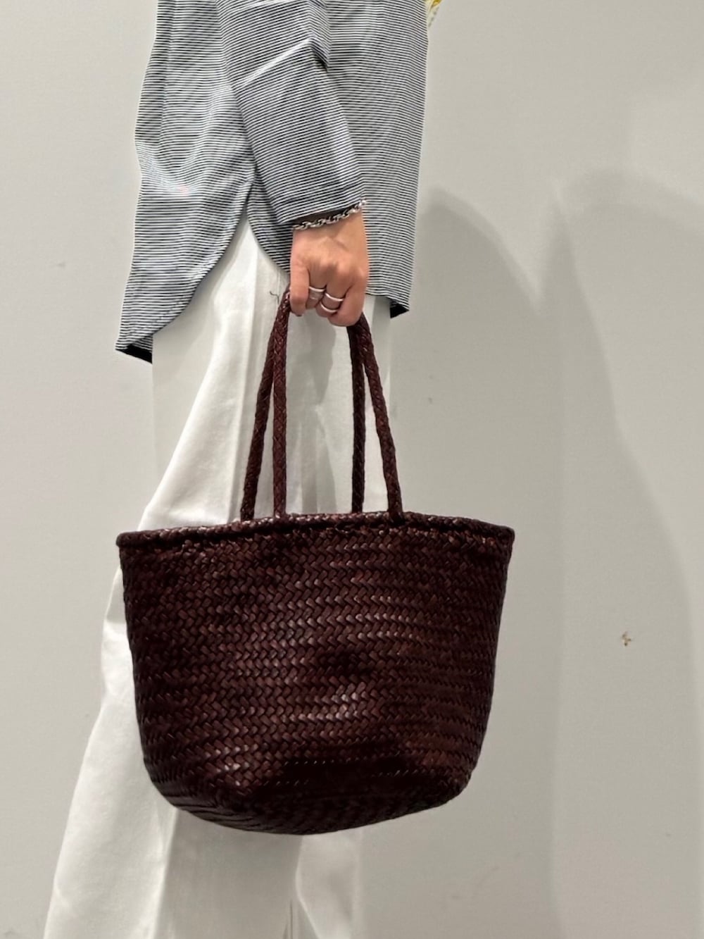 ブラウン系のトートバッグ、ホワイト系のデニムパンツ、ブラック系のローファーを着用したレディースの秋コーディネートの2枚目の写真