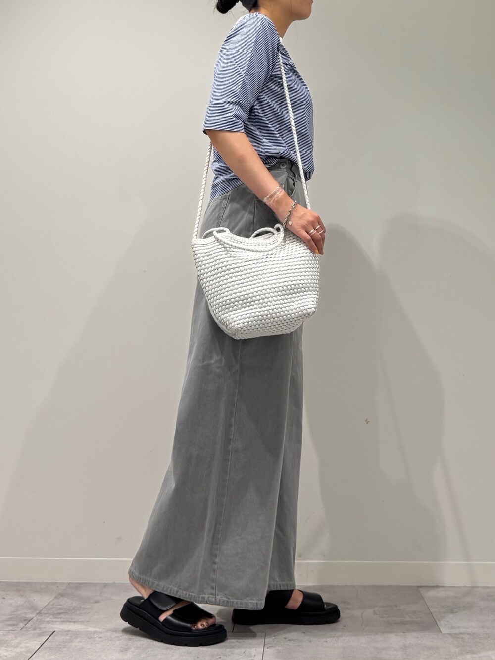 ホワイト系のトートバッグ、グレー系のデニムパンツ、ブラック系のサンダルを着用したレディースの夏コーディネートの2枚目の写真