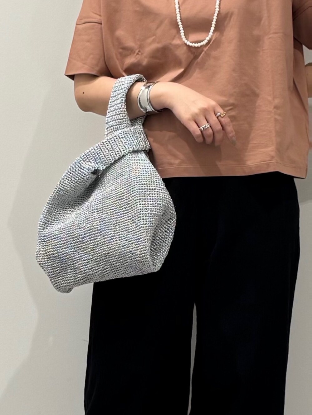 シルバー系のかごバッグ、ブラック系のサンダル、ゴールド系のネックレスを着用したレディースの春コーディネートの9枚目の写真