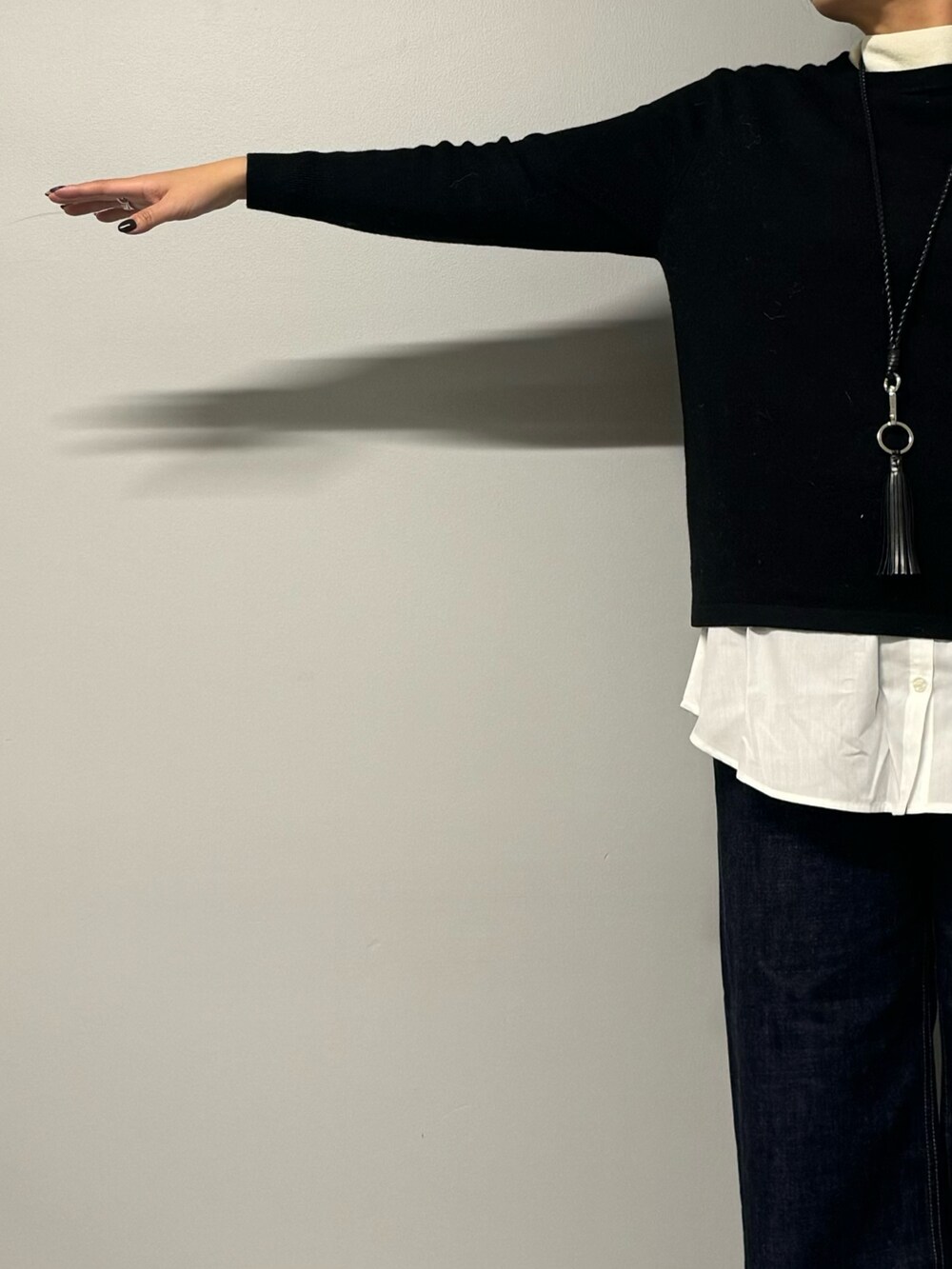 ブラック系のニット/セーター、ブルー系のデニムパンツ、ブラック系のショルダーバッグを着用したレディースの秋コーディネートの6枚目の写真