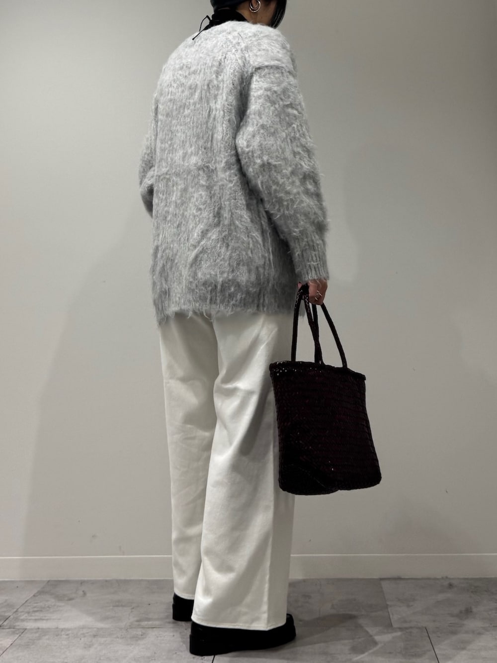 パープル系のトートバッグ、ホワイト系のデニムパンツ、ブラック系のローファーを着用したレディースの冬コーディネートの4枚目の写真