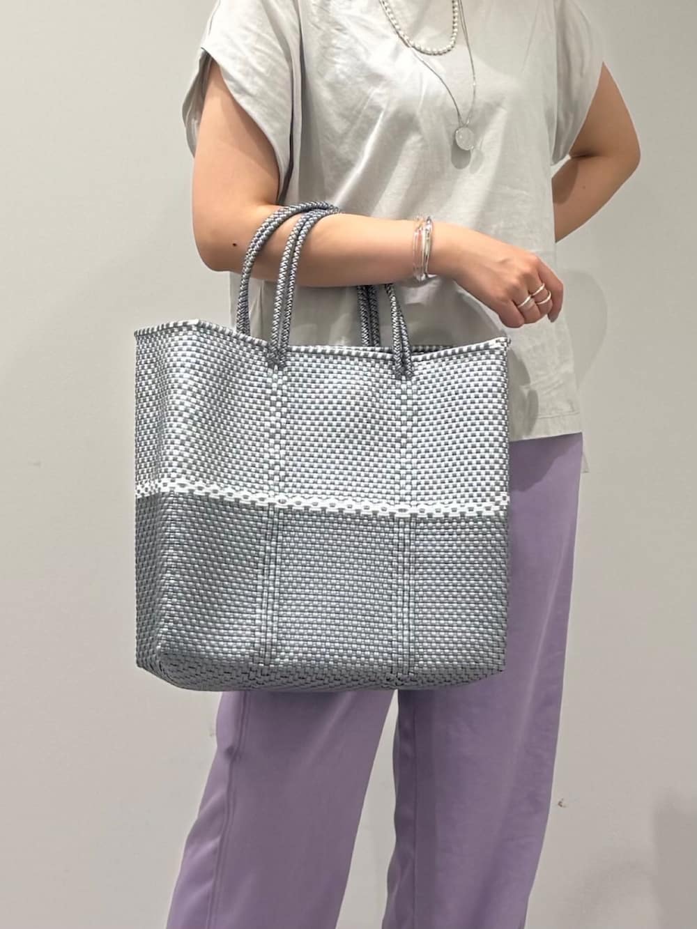 グレー系のTシャツ/カットソー、シルバー系のかごバッグ、ブラック系のサンダルを着用したレディースの夏コーディネートの7枚目の写真