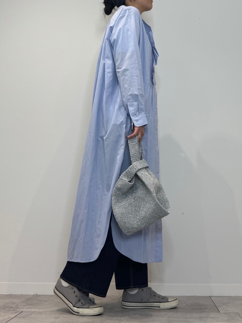 ブルー系のシャツワンピース、シルバー系のかごバッグ、ブルー系のデニムパンツを着用したレディースの春コーディネートの2枚目の写真