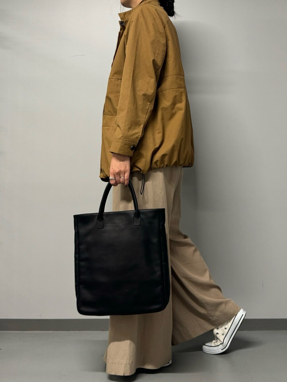ブラック系のトートバッグ、ベージュ系のブルゾン、ブラック系のTシャツ/カットソーを着用したレディースの秋コーディネートの6枚目の写真