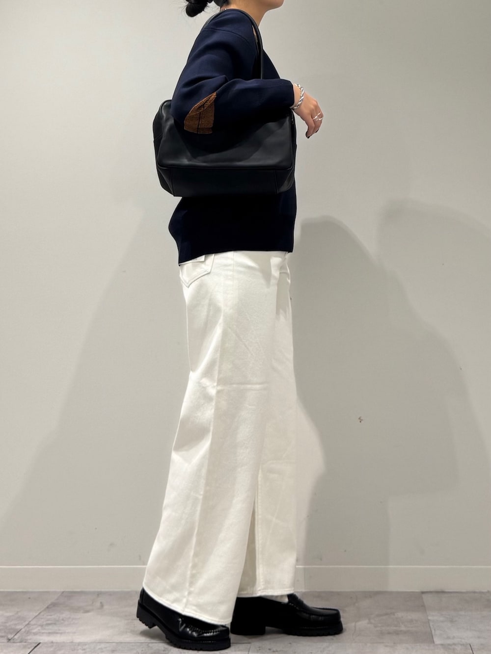 ブラック系のボストンバッグ、ホワイト系のデニムパンツ、ブラック系のローファーを着用したレディースの冬コーディネートの7枚目の写真