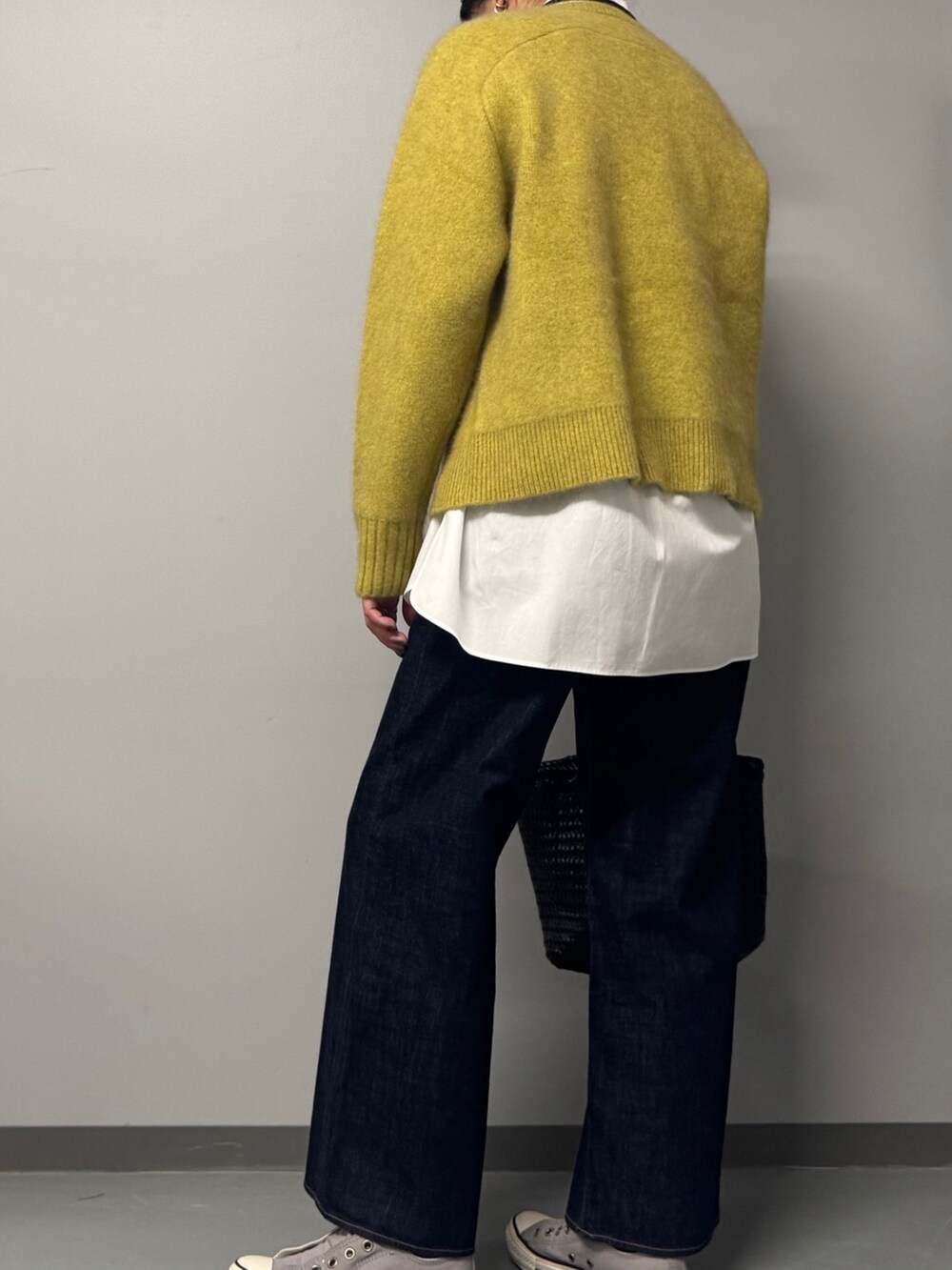 イエロー系のニット/セーター、ホワイト系のシャツ/ブラウス、ブルー系のデニムパンツを着用したレディースの冬コーディネートの6枚目の写真