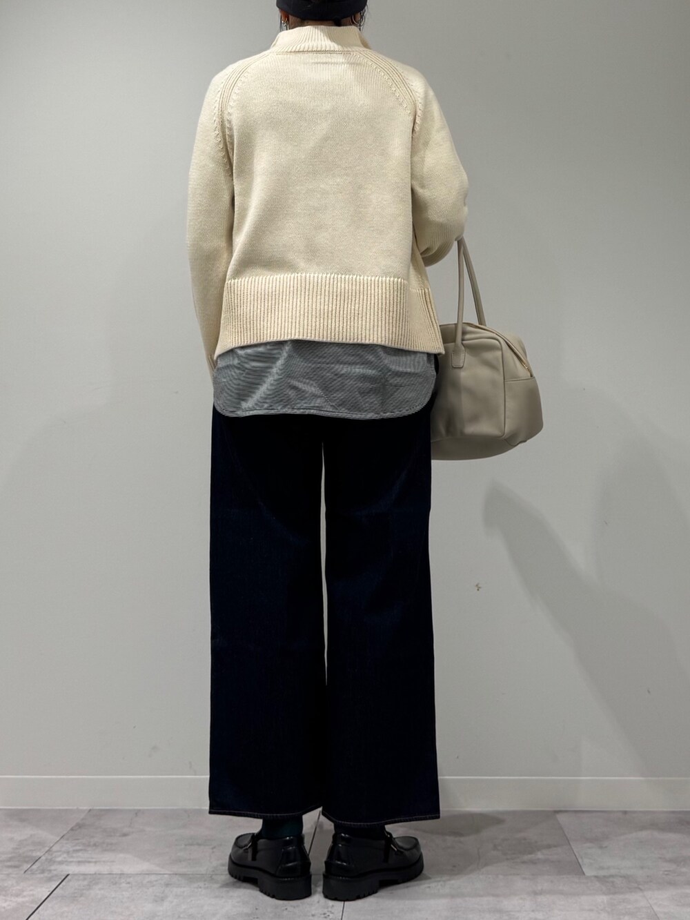 ベージュ系のボストンバッグ、ブルー系のデニムパンツ、ブラック系のローファーを着用したレディースの冬コーディネートの3枚目の写真