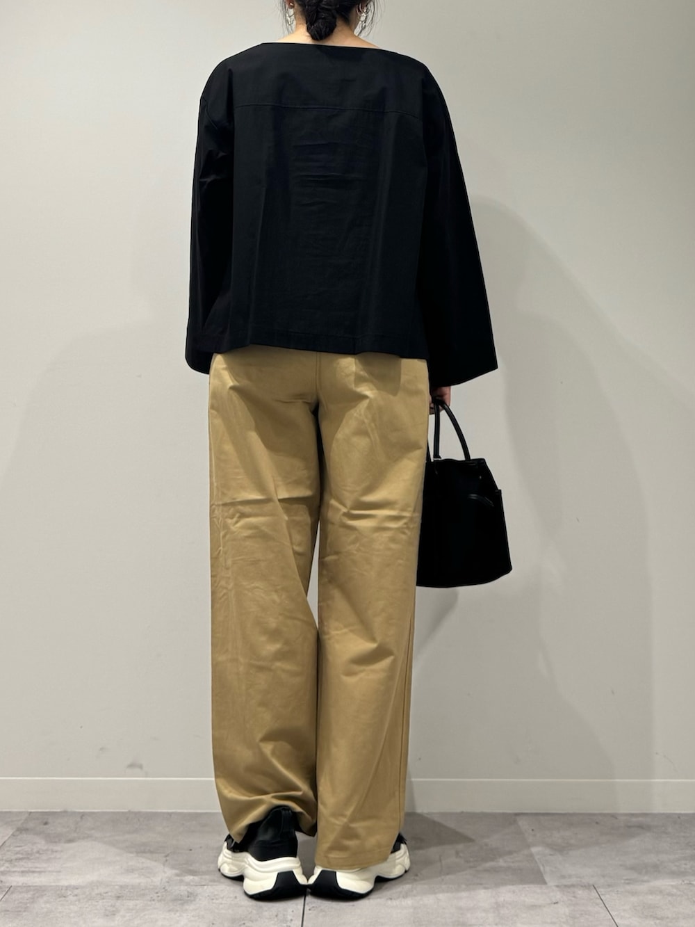 ブラック系のスニーカー、ベージュ系のチノパンツ、ブラック系のシャツ/ブラウスを着用したレディースの秋コーディネートの3枚目の写真