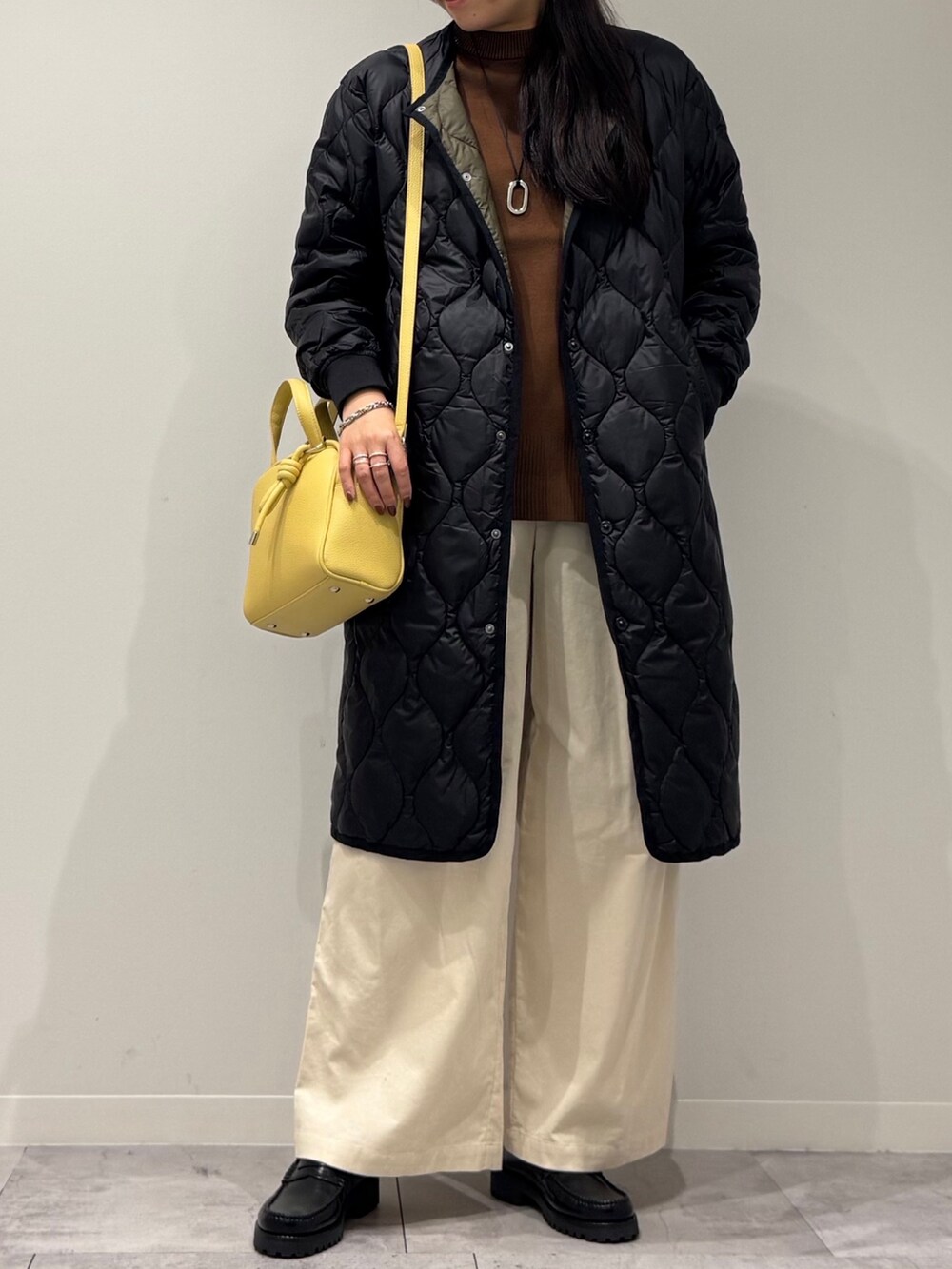 イエロー系のボストンバッグ、ブラウン系のベスト、ホワイト系のその他パンツを着用したレディースの秋コーディネートの6枚目の写真