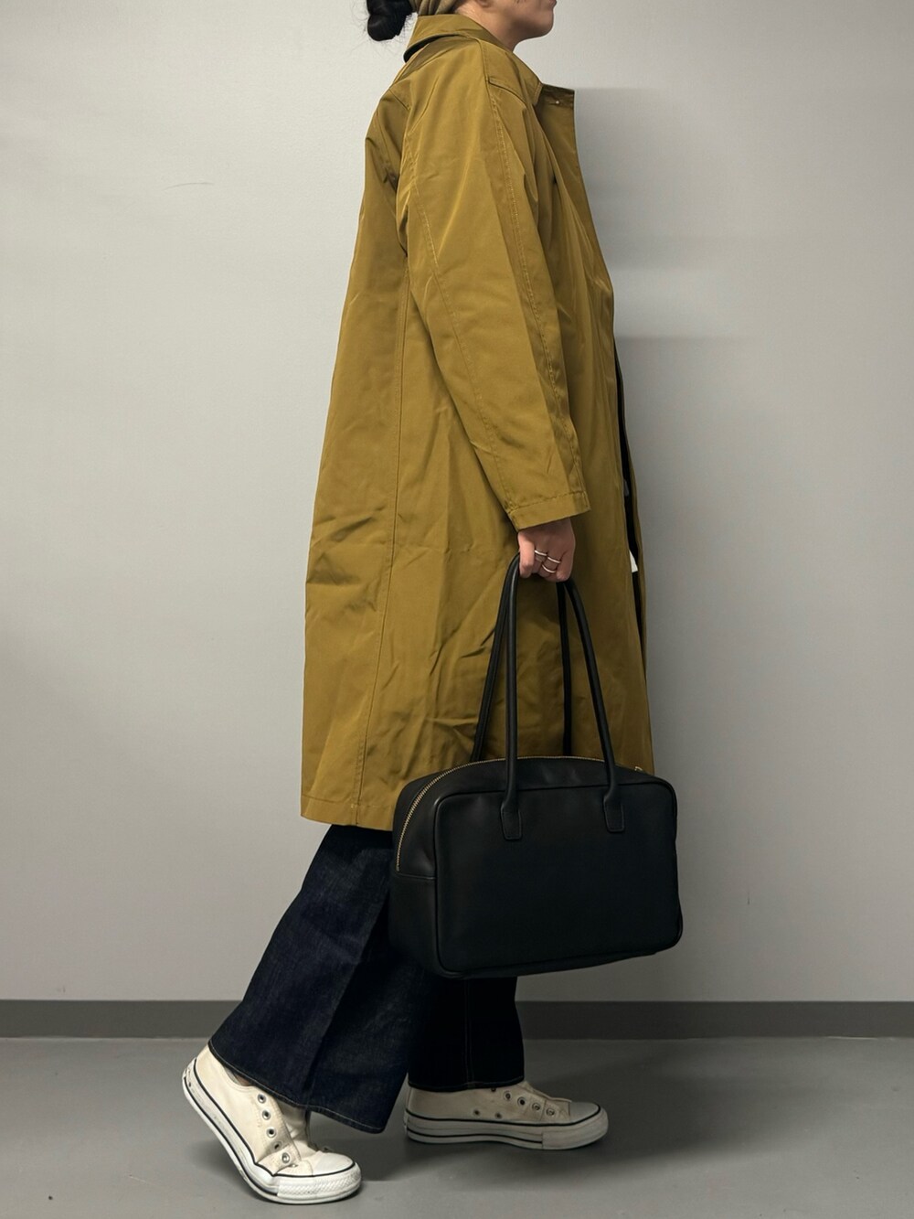 ベージュ系のダウンジャケット/コート、ブラック系のボストンバッグ、ブルー系のデニムパンツを着用したレディースの秋コーディネートの5枚目の写真