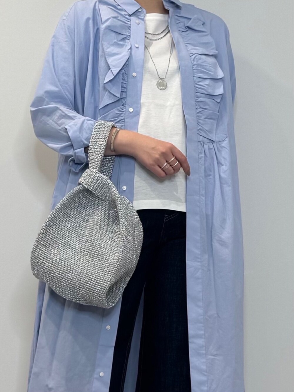ブルー系のシャツワンピース、シルバー系のかごバッグ、ブルー系のデニムパンツを着用したレディースの春コーディネートの10枚目の写真