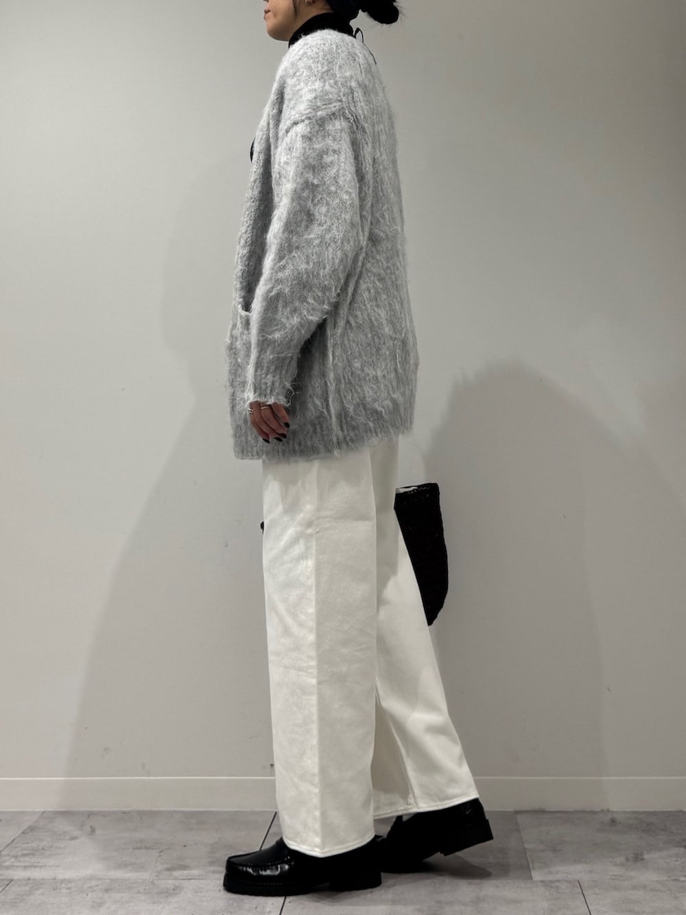 パープル系のトートバッグ、ホワイト系のデニムパンツ、ブラック系のローファーを着用したレディースの冬コーディネートの6枚目の写真