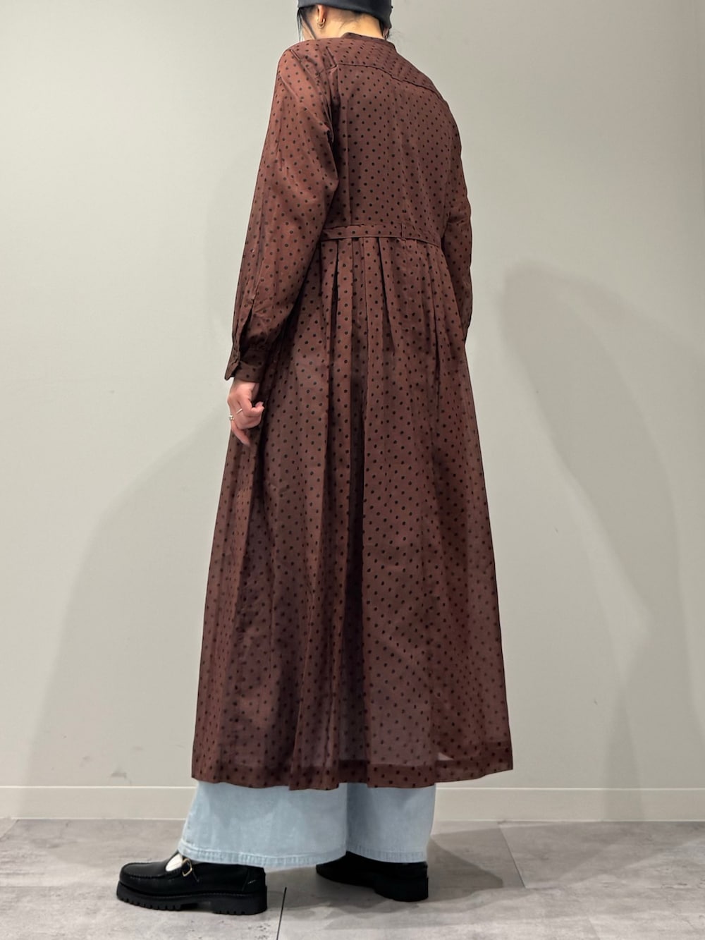 ブラウン系のワンピース、ブルー系のデニムパンツ、ブラック系のローファーを着用したレディースの春コーディネートの5枚目の写真