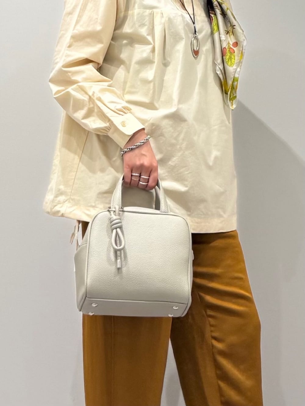 グレー系のボストンバッグ、ホワイト系のシャツ/ブラウス、ブラウン系のその他パンツを着用したレディースの秋コーディネートの7枚目の写真