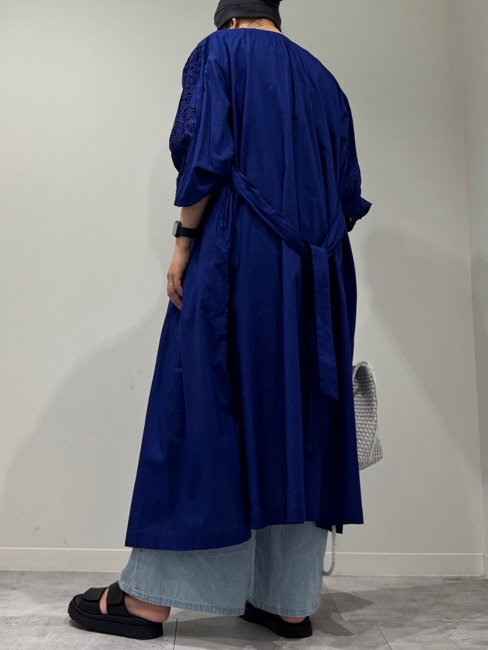 ホワイト系のトートバッグ、ブルー系のデニムパンツ、ブラック系のサンダルを着用したレディースの秋コーディネートの5枚目の写真