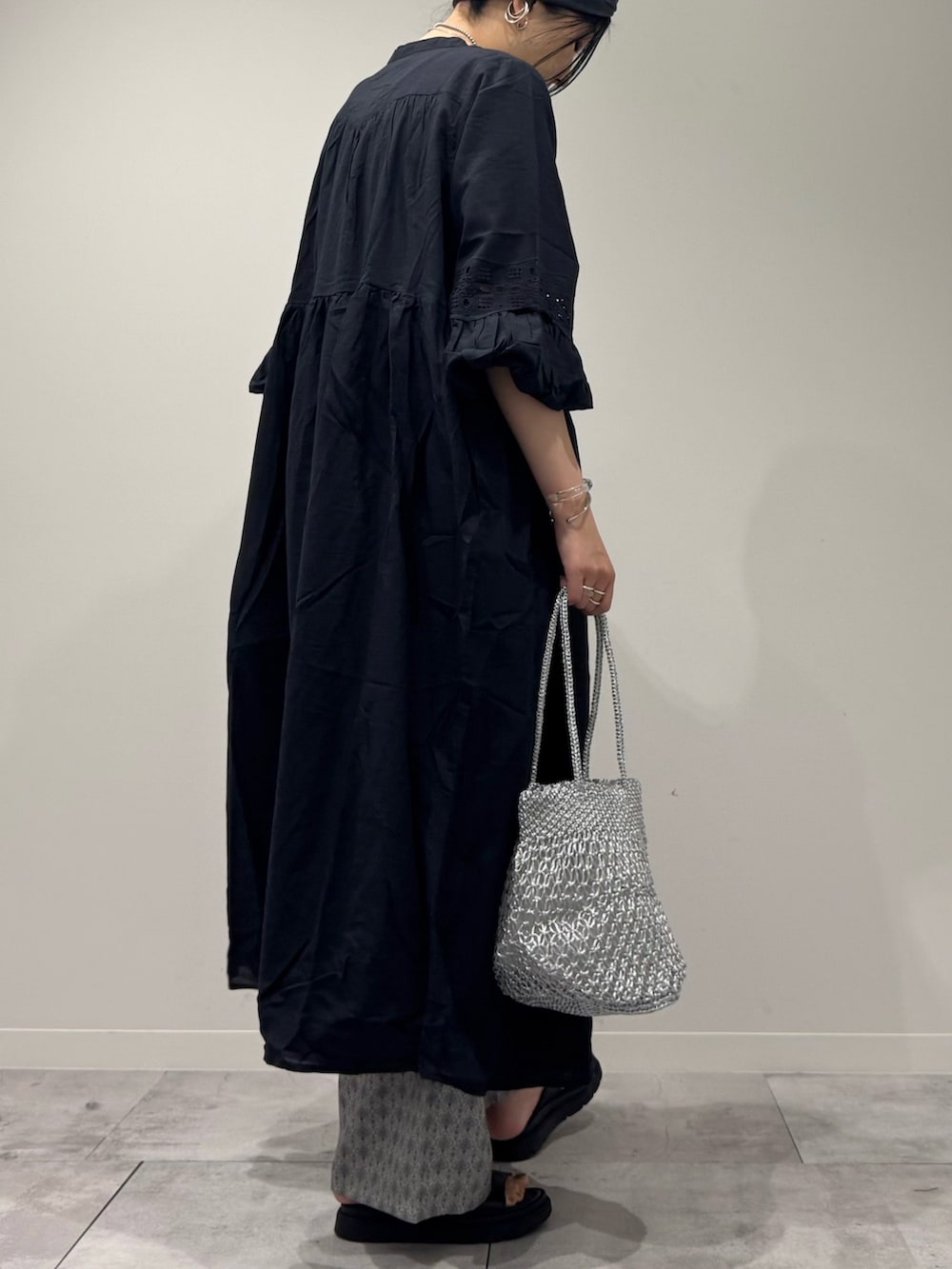 ブラック系のワンピース、シルバー系のかごバッグ、ブラック系のサンダルを着用したレディースの秋コーディネートの3枚目の写真