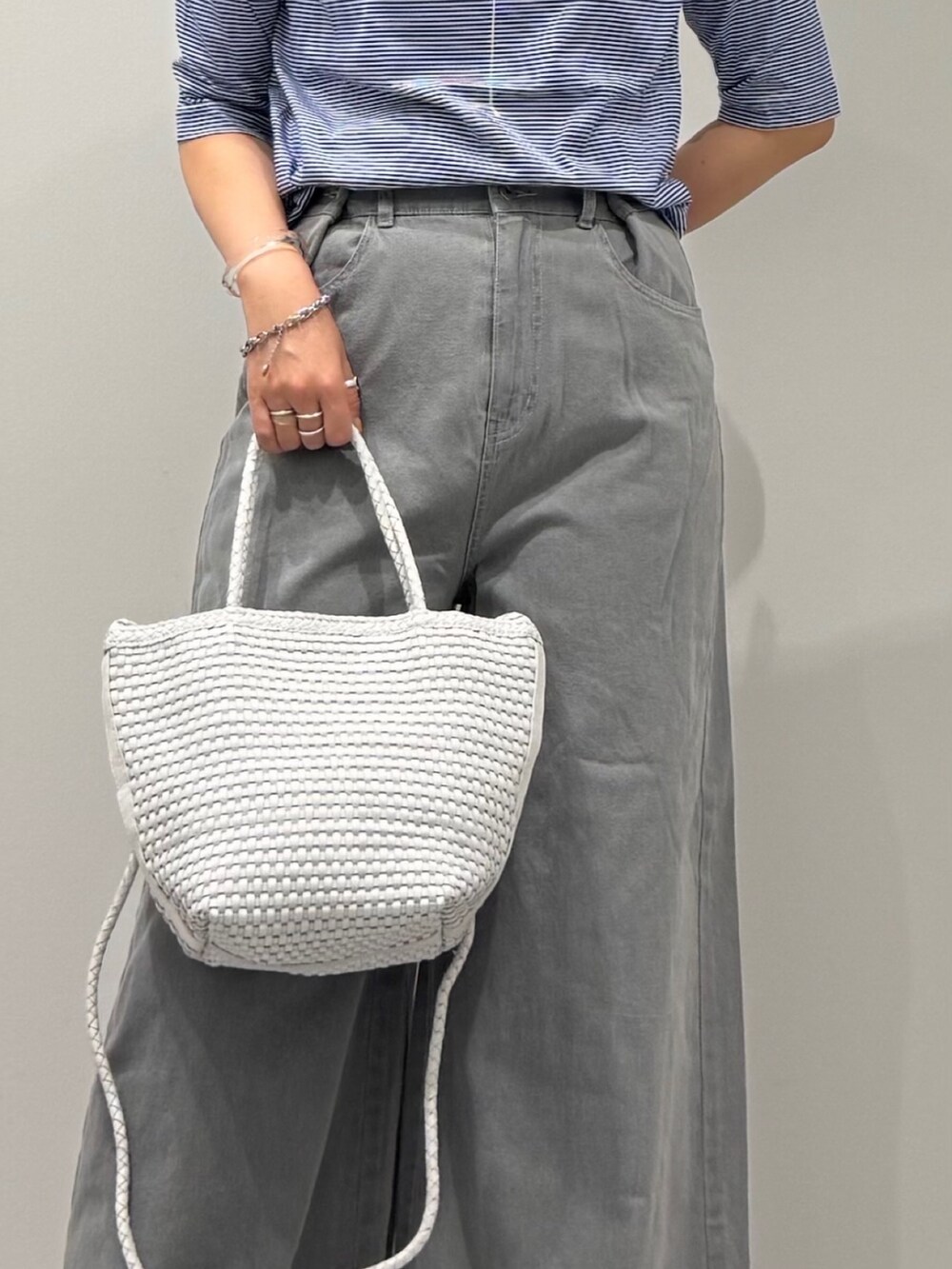 ホワイト系のトートバッグ、グレー系のデニムパンツ、ブラック系のサンダルを着用したレディースの夏コーディネートの6枚目の写真