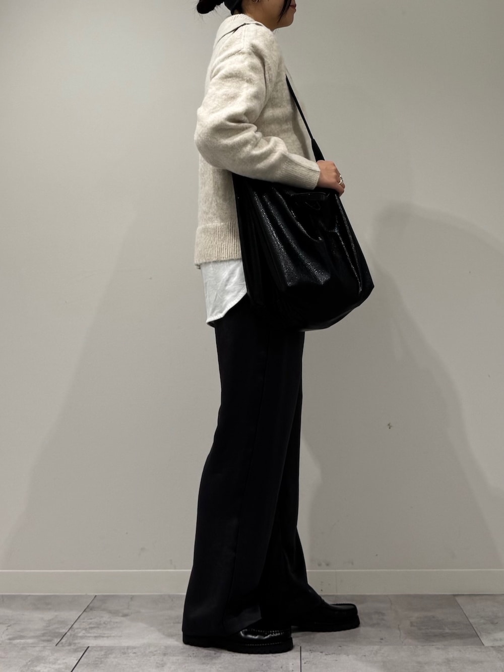 ブラック系のトートバッグ、ホワイト系のニット/セーター、ホワイト系のTシャツ/カットソーを着用したレディースの冬コーディネートの2枚目の写真