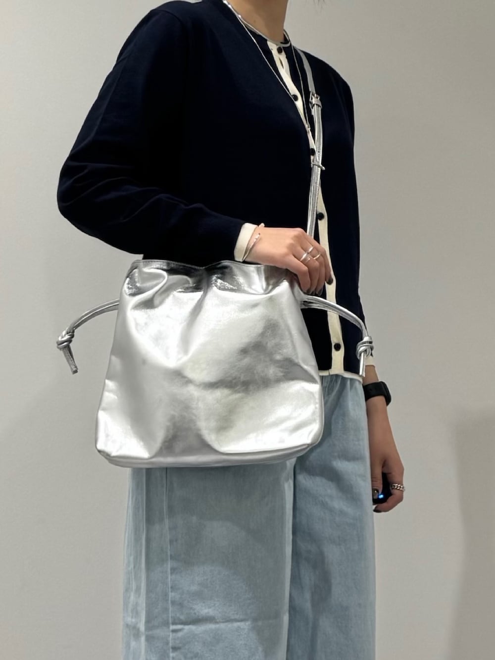 シルバー系のショルダーバッグ、ブルー系のデニムパンツ、ブルー系のカーディガン/ボレロを着用したレディースの春コーディネートの7枚目の写真