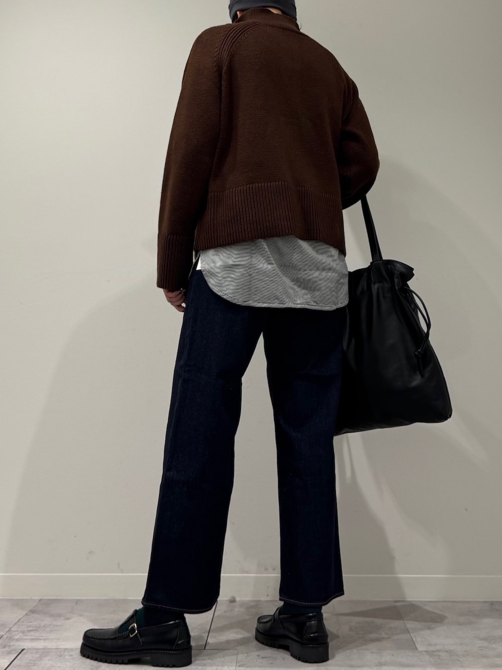 ブラック系のトートバッグ、ブルー系のデニムパンツ、ブラック系のローファーを着用したレディースの冬コーディネートの4枚目の写真