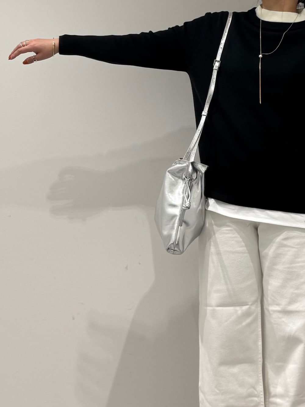 シルバー系のショルダーバッグ、ホワイト系のデニムパンツ、ブラック系のローファーを着用したレディースの冬コーディネートの6枚目の写真