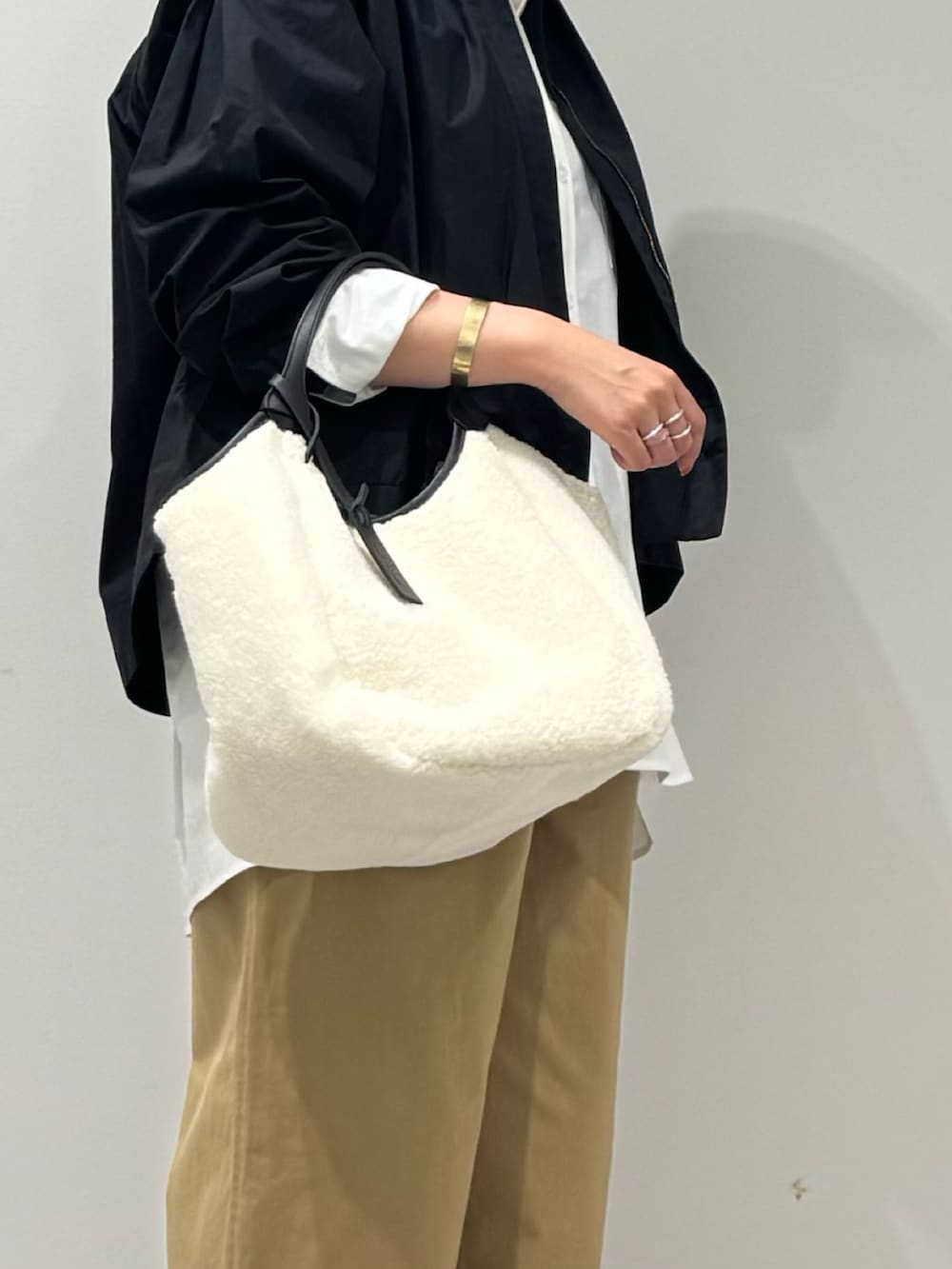 ホワイト系のトートバッグ、ブラック系のブルゾン、ベージュ系のチノパンツを着用したレディースの秋コーディネートの8枚目の写真