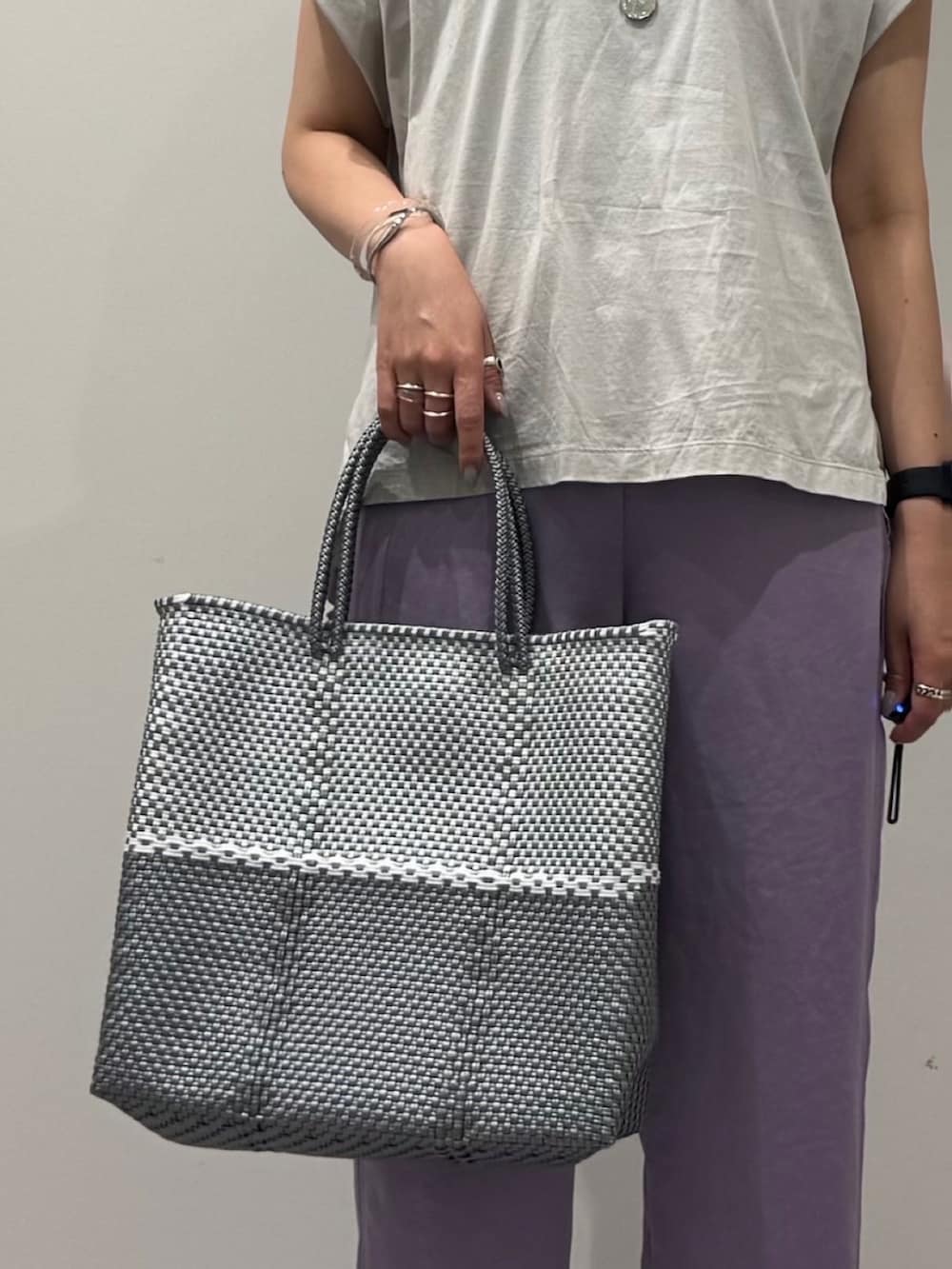 グレー系のTシャツ/カットソー、シルバー系のかごバッグ、ブラック系のサンダルを着用したレディースの夏コーディネートの6枚目の写真