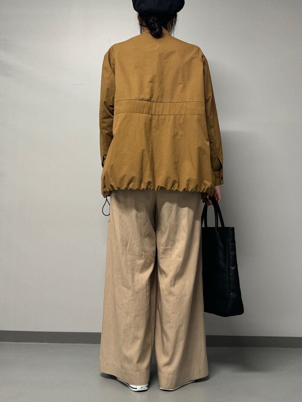 ブラック系のトートバッグ、ベージュ系のブルゾン、ブラック系のTシャツ/カットソーを着用したレディースの秋コーディネートの3枚目の写真