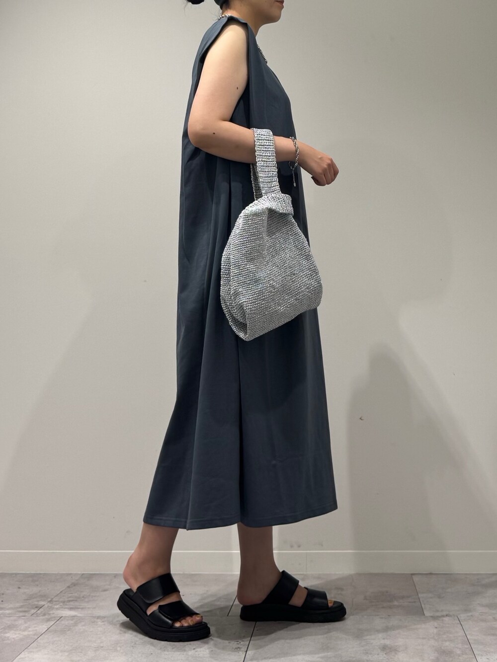 シルバー系のかごバッグ、ブラック系のサンダル、ブルー系のワンピースを着用したレディースの夏コーディネートの2枚目の写真