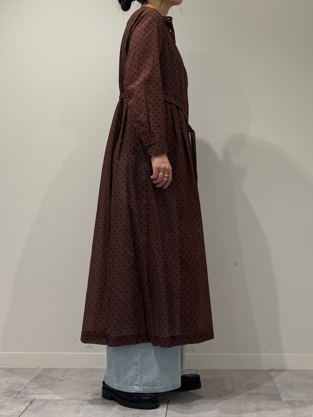 ブラウン系のワンピース、ブルー系のデニムパンツ、ブラック系のローファーを着用したレディースの春コーディネートの3枚目の写真