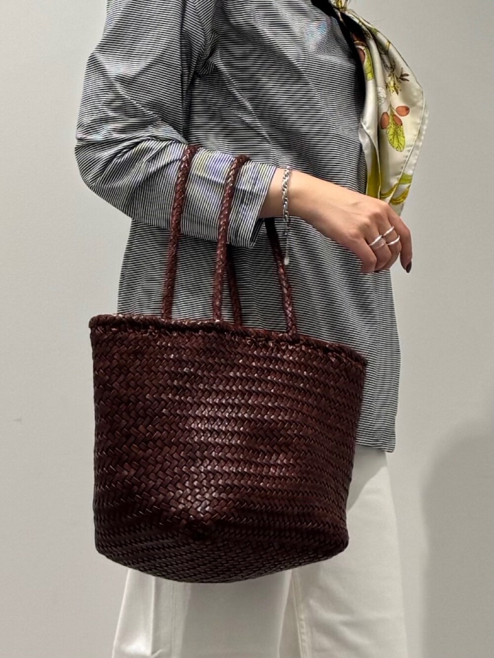 ブラウン系のトートバッグ、ホワイト系のデニムパンツ、ブラック系のローファーを着用したレディースの秋コーディネートの7枚目の写真