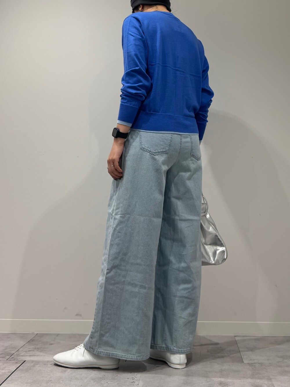 シルバー系のショルダーバッグ、ブルー系のカーディガン/ボレロ、ブルー系のデニムパンツを着用したレディースの冬コーディネートの4枚目の写真