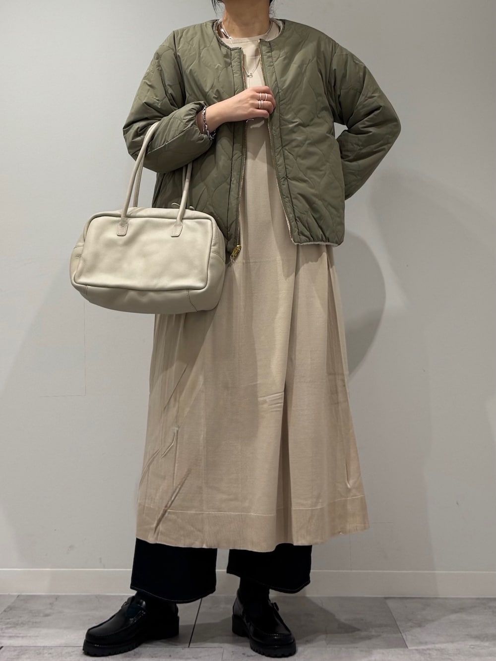 ベージュ系のボストンバッグ、ベージュ系のワンピース、ブルー系のデニムパンツを着用したレディースの春コーディネートの2枚目の写真