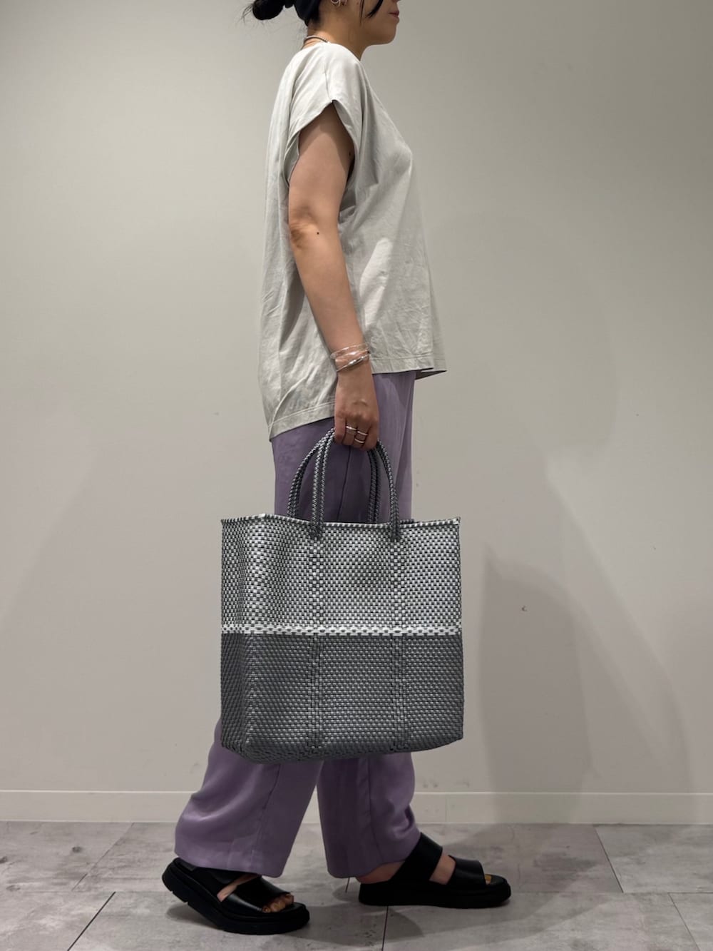 グレー系のTシャツ/カットソー、シルバー系のかごバッグ、ブラック系のサンダルを着用したレディースの夏コーディネートの2枚目の写真