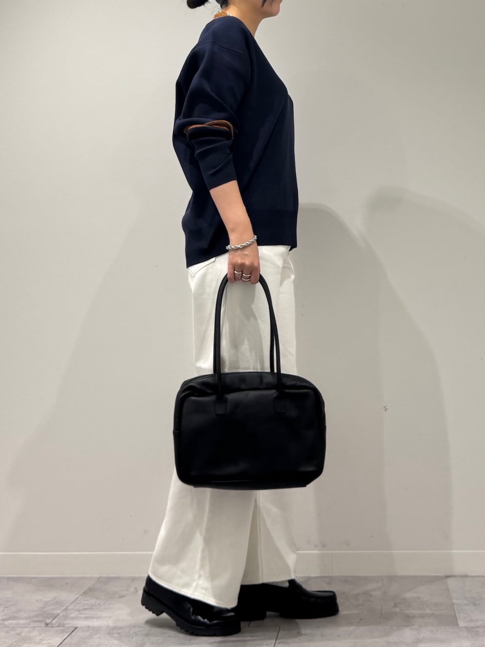 ブラック系のボストンバッグ、ホワイト系のデニムパンツ、ブラック系のローファーを着用したレディースの冬コーディネートの2枚目の写真