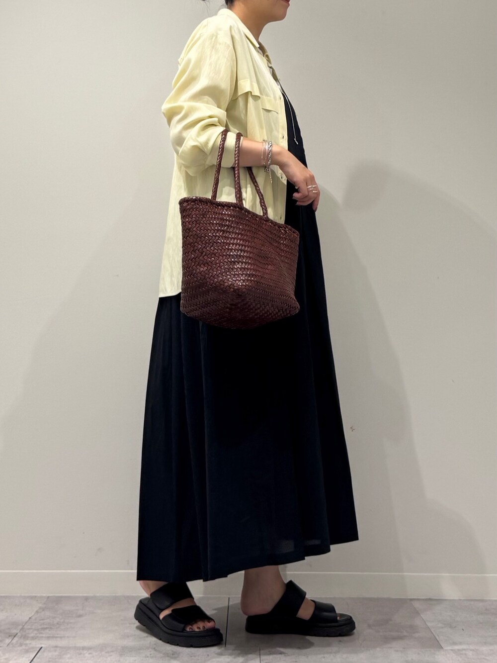 ブラウン系のトートバッグ、ブラック系のワンピース、イエロー系のシャツ/ブラウスを着用したレディースの秋コーディネートの2枚目の写真