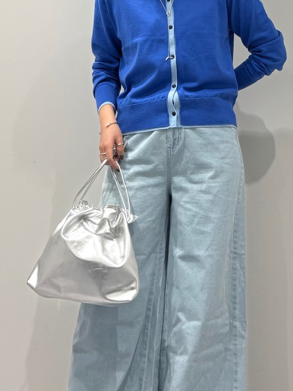 シルバー系のショルダーバッグ、ブルー系のカーディガン/ボレロ、ブルー系のデニムパンツを着用したレディースの冬コーディネートの9枚目の写真