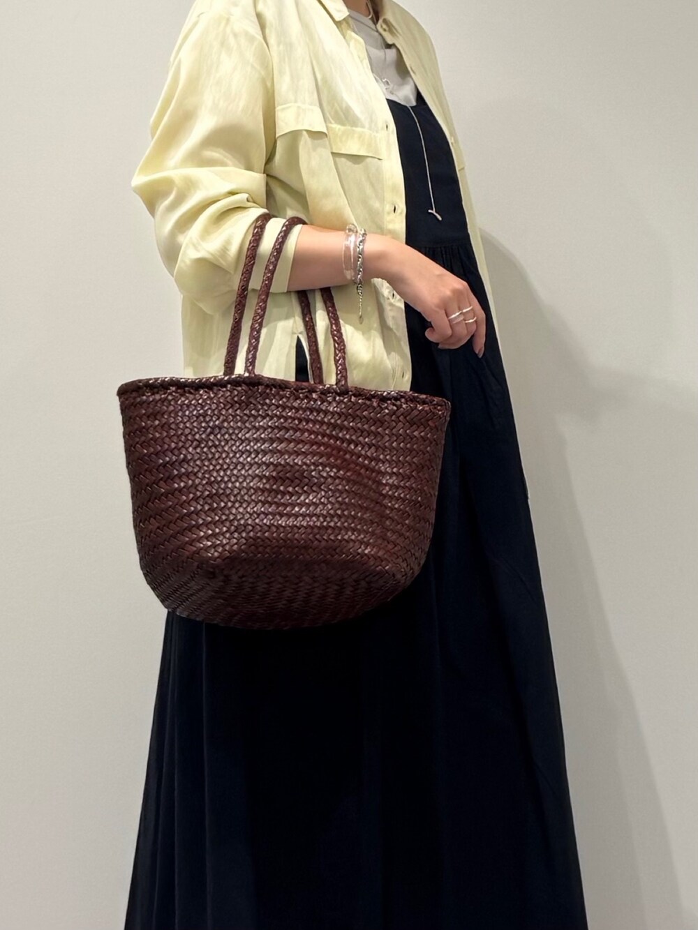 ブラウン系のトートバッグ、ブラック系のワンピース、イエロー系のシャツ/ブラウスを着用したレディースの秋コーディネートの6枚目の写真